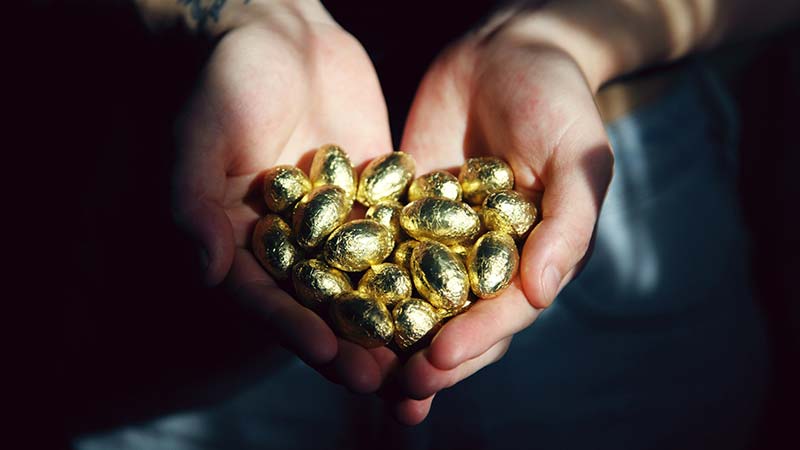 hands holding a pile of gold eggs
